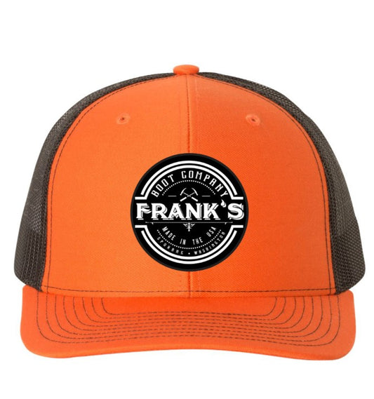 An orange and black trucker hat featuring a circular black and white 'Frank's Hot Company' logo patch on the front, set against a plain white background.